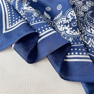 Detailed view of dark blue paisley silk scarf with satin finish and fine stitched edges