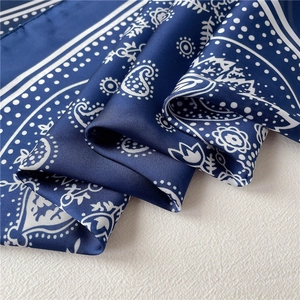 Detail of dark blue silk scarf with white paisley pattern and smooth lustrous texture