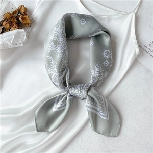 Close-up of a light green paisley faux silk scarf with elegant floral prints and stripes