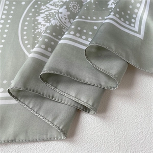 Detailed close-up of bean green satin scarf with white paisley patterns and soft texture