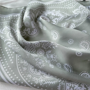 Macro shot of sage green paisley satin scarf with smooth silk texture and soft drape