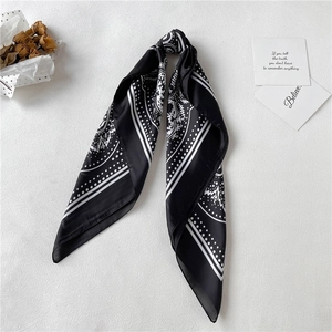 Detail of a black and white paisley silk scarf featuring a sleek satin finish texture