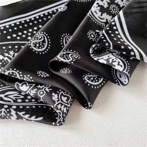 Macro detail showing smooth silky texture and classic paisley pattern of the square scarf