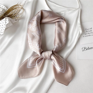 Detail of champagne paisley silk scarf tied on white satin dress with floral patterns