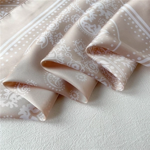 Detailed view of champagne silk scarf featuring white paisley pattern and soft drapes