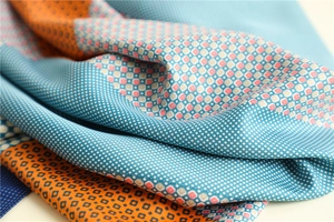 Macro detail of silk-like scarf fabric showing geometric patterns and smooth texture