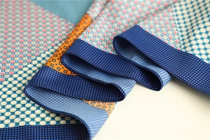 Macro shot of geometric silk scarf detail showing colorful twill weave and smooth texture