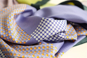 Detail of silk-like scarf fabric showing purple geometric patterns and smooth texture