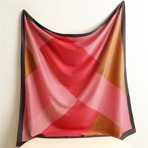 Detailed close-up of a large square silk scarf with red and pink geometric patterns