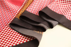 Detail of premium silk scarf featuring geometric patterns with red polka dots and grids