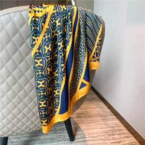 Detail of silk scarf with geometric H pattern and chain print draped on a chair