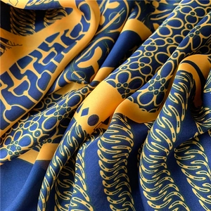 Detail of silk-like scarf fabric showing intricate floral prints in blue and gold colors