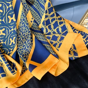 Close-up of silk scarf with luxury chain print and H letter pattern in blue and yellow