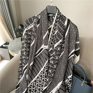 Detail of elegant black and white silk scarf showing H-letter patterns and chain motifs