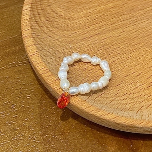 Detailed view of baroque freshwater pearl ring with vibrant orange teardrop gemstone charm