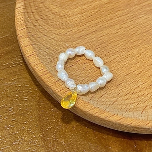 Detailed macro view of an irregular freshwater pearl ring with yellow teardrop pendant