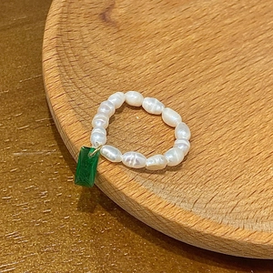 Detailed macro view of baroque pearl beaded ring featuring a green zircon gemstone charm