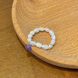 Macro detail of a freshwater pearl beaded ring featuring a sparkling purple zircon pendant