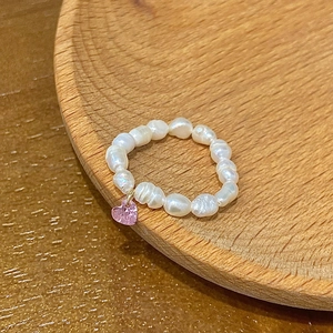 Detailed macro view of baroque freshwater pearl ring with a pink heart crystal pendant