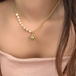 Detail view of heart pendant necklace with gold chain and freshwater pearls on model