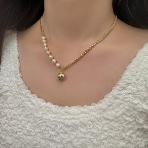 Detail of gold heart pendant necklace with elegant white pearls on a model wearing white