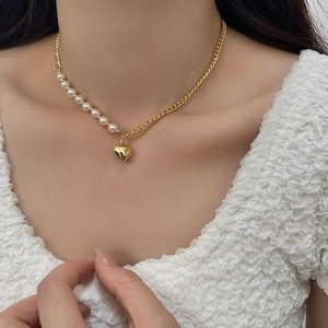Detail of a heart pendant necklace with pearls and golden curb chain on a model