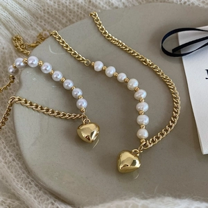 Detail of French style gold heart pendant with freshwater pearls on elegant chain