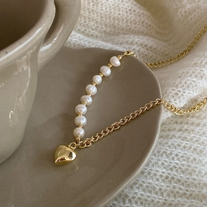 Detail of freshwater pearl chain necklace with heart pendant on a ceramic saucer