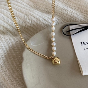 Close-up of a French style gold heart pendant necklace with elegant pearl chain detail