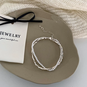 Elegant silver double-layer bracelet with white pearls and metallic beads on a tray