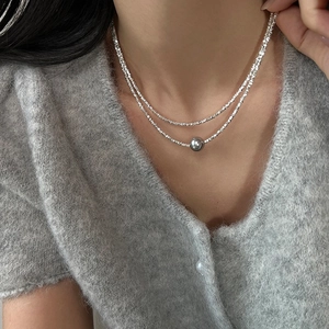 Détail d'un collier à deux rangs argenté avec perle grise sur le cou du mannequin