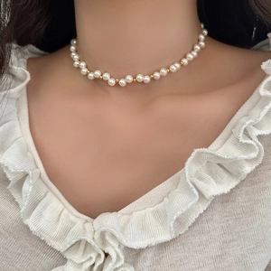 Detail of white pearls and gold beads choker necklace worn on elegant lace collar neck