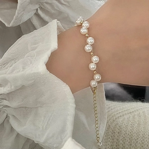 Elegant white pearl bracelet with gold spacers on model, featuring an adjustable chain link