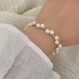 Close-up of elegant freshwater pearl bracelet with gold beads on knit fabric
