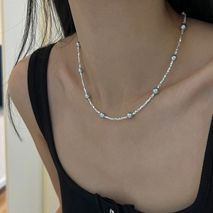 Gros plan d'un collier ras du cou minimaliste en perles d'argent avec accents argentés concassés