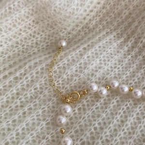 Detailed close-up of pearl necklace with gold spring clasp and adjustable extension chain