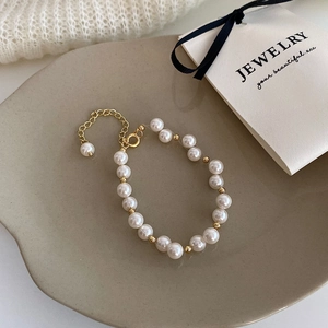Detail of white pearl bracelet with gold spacer beads on grey ceramic tray