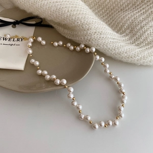 Close-up of pearl necklace with gold beads, lobster clasp and adjustable chain on a tray