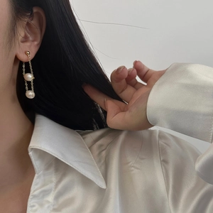 Detail of freshwater pearl drop earrings with elegant gold chain tassel on model