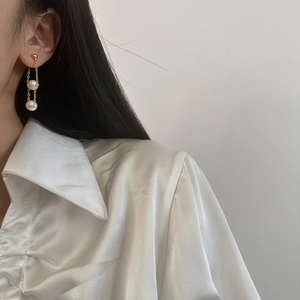 Close-up of elegant gold chain drop earrings featuring two white pearls on model
