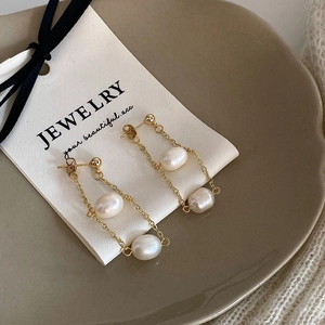 Detail of gold chain tassel earrings with freshwater baroque pearls on jewelry card