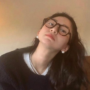 Detailed view of layered pearl necklace and studs with vintage round tortoise glasses