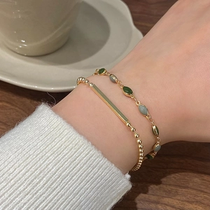 Double-layered French retro bracelet with gold beads and green gemstone accents on wrist