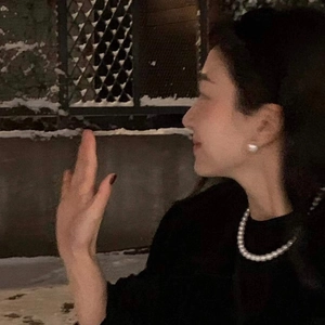 Close-up of elegant pearl necklace and matching stud earrings worn in a snowy night scene