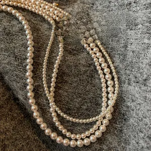 Close-up of lustrous round cream-white pearl necklace on a grey textured background