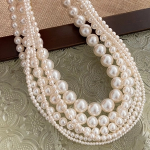 Detail of multi-layer round pearl necklace displayed on vintage embossed glass