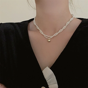 Primo piano della collana di perle a doppio strato con pendente a cuore d'oro