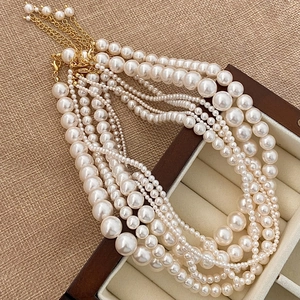 Detail of layered pearl necklaces with golden lobster clasp on a vintage jewelry box