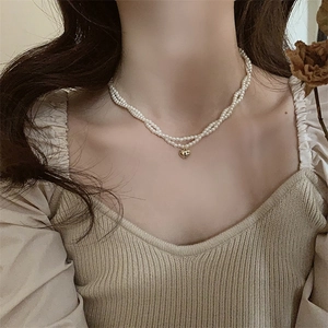 Primo piano della collana di perle a doppio strato con ciondolo a cuore d'oro al collo