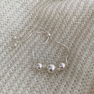 Detail of adjustable silver beaded bracelet with three polished beads on a box chain